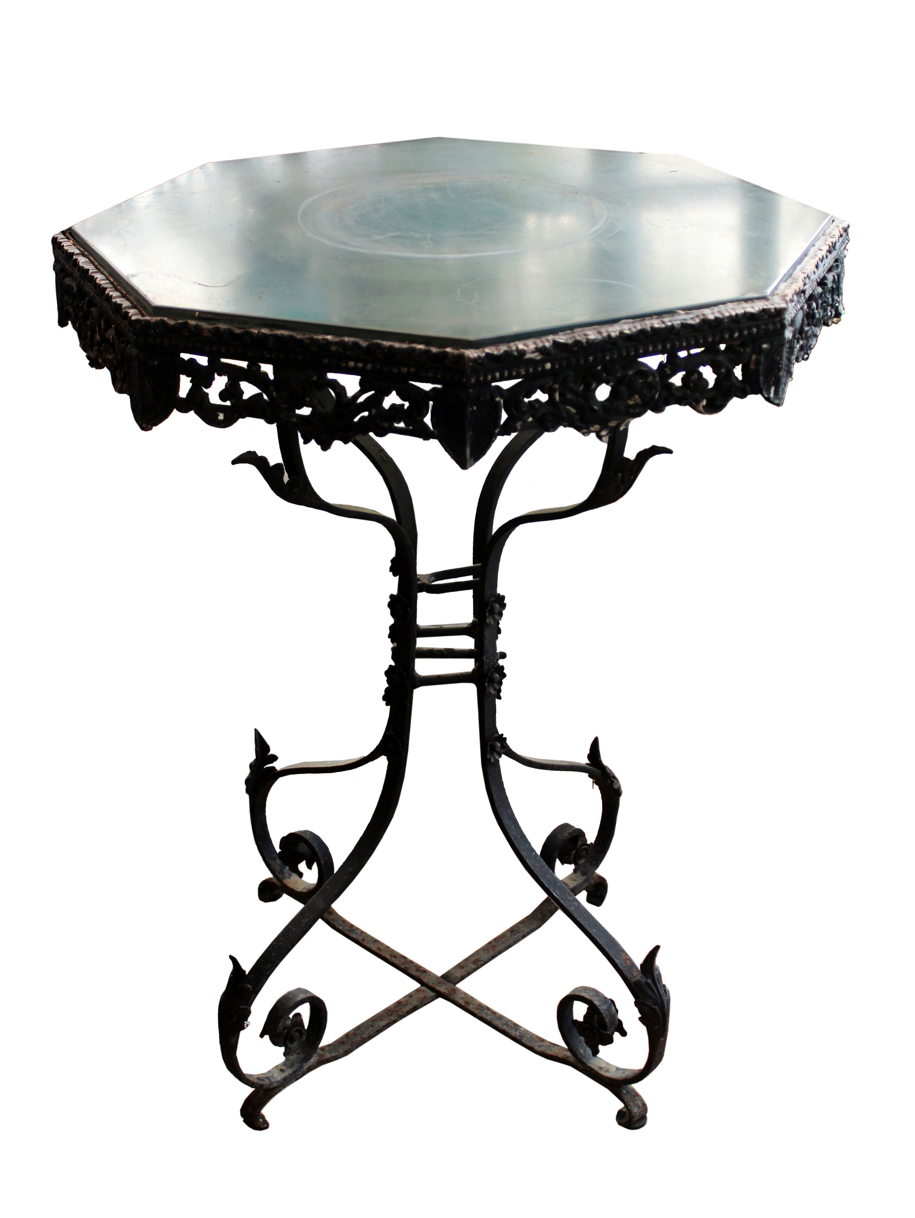 An octagonal marble top table with carved apron decorations and iron legs.