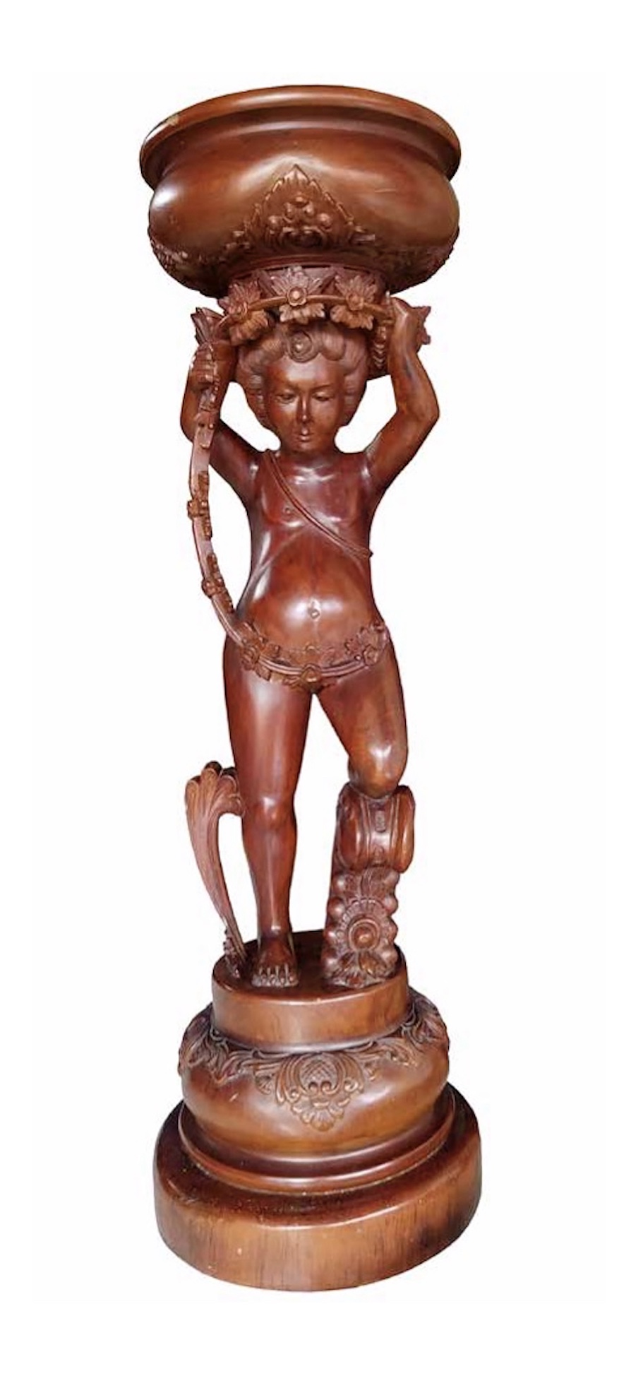 An antique carved wooden sculpture depicting a child with a basket on his head