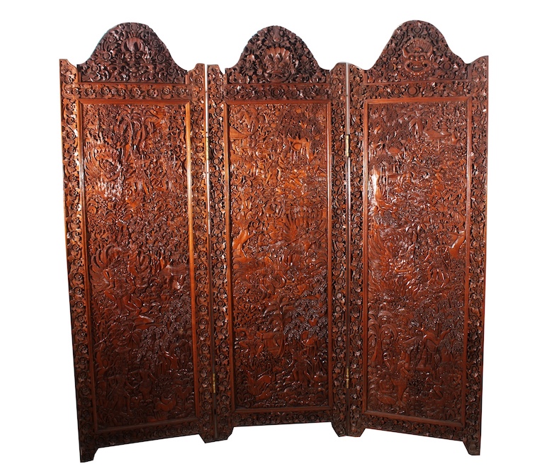 A 20th century Balinese carved teak floor screen with three panels of wayang figures in forrest