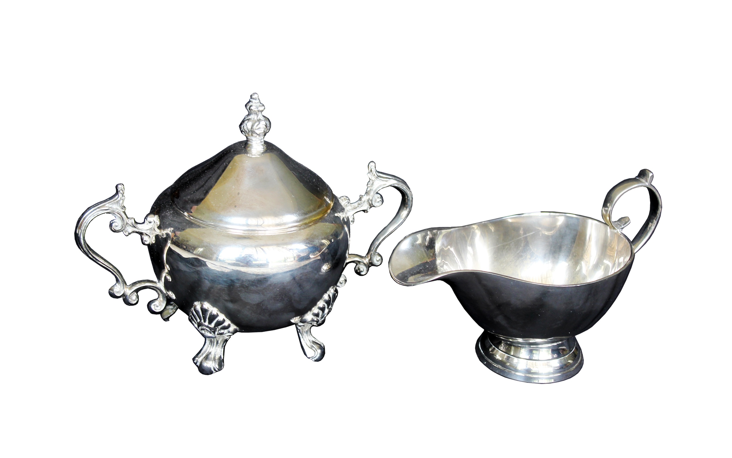 A silver plated sugar bowl with lid and a sauce boat.