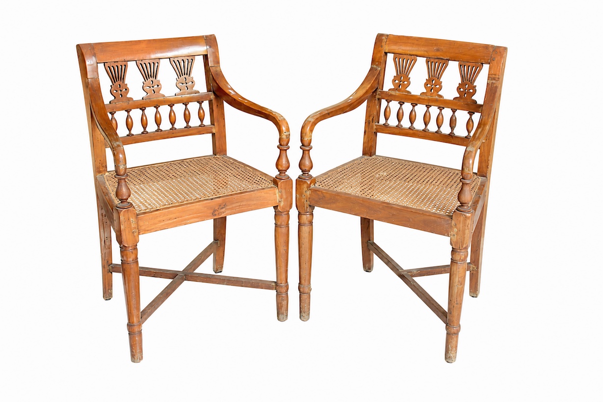A pair of early 20th century carved teak art nouveau armchairs with rattan seat